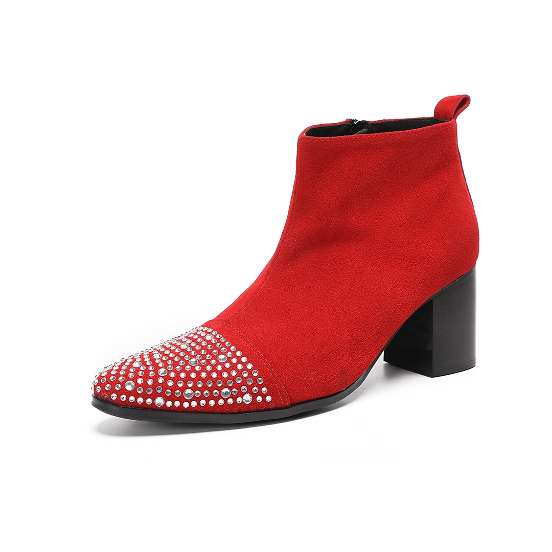 A pair of vibrant red suede ankle boots with silver rhinestones on the pointed toe and a black block heel.