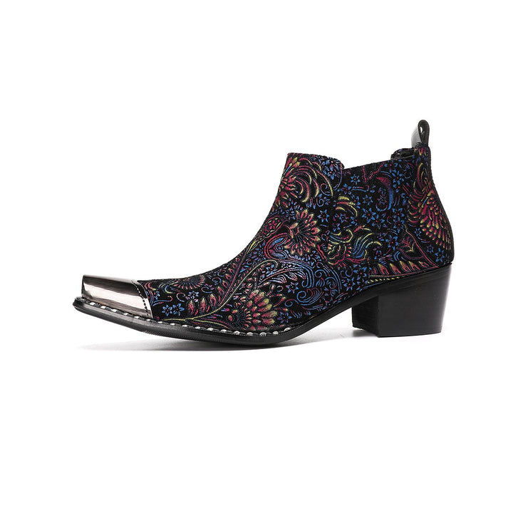 A pair of men's black ankle boots with a vibrant multicolor brocade pattern and a polished silver metal toe cap.