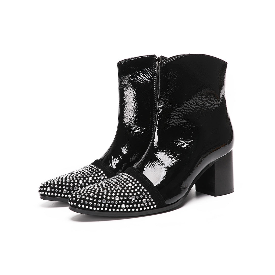 A pair of black patent leather ankle boots with rhinestone-embellished pointed toes and block heels.