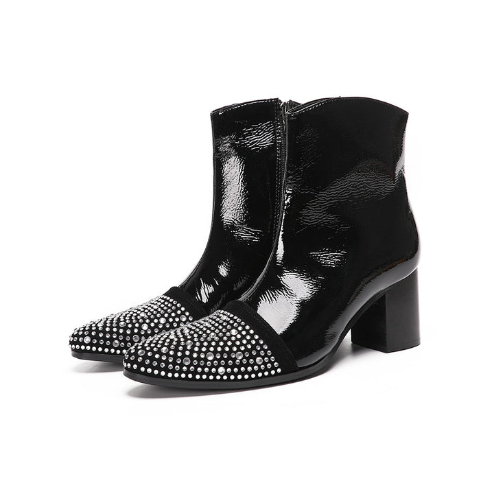 A pair of black patent leather ankle boots with rhinestone-embellished pointed toes and block heels.
