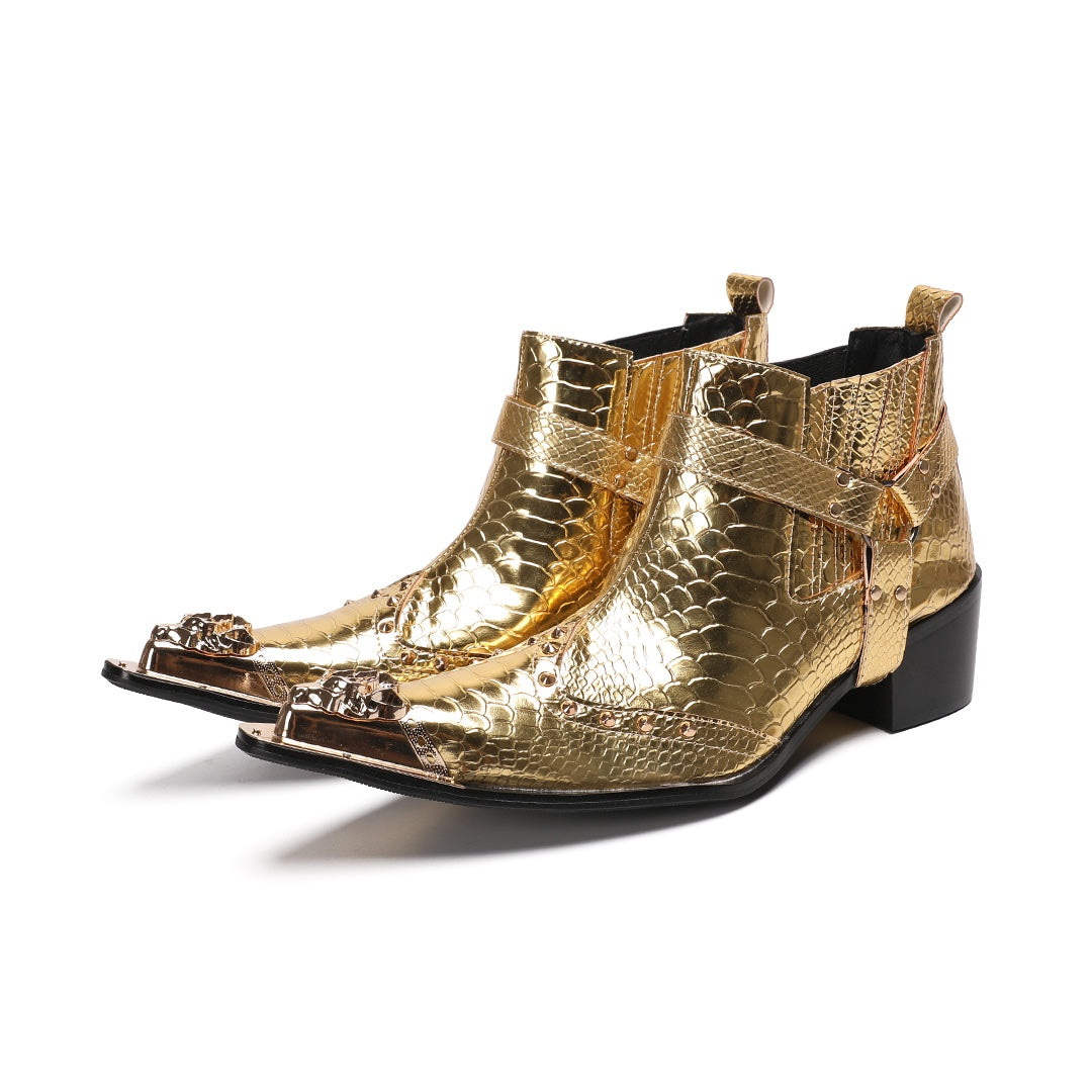 A pair of shiny gold snake skin textured ankle boots with a pointed metal toe cap, studded details, and an ankle strap.
