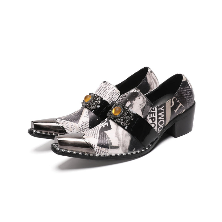 Pair of men's black and white newspaper print slip-on dress shoes with pointed silver metal toe caps and decorative buckles.