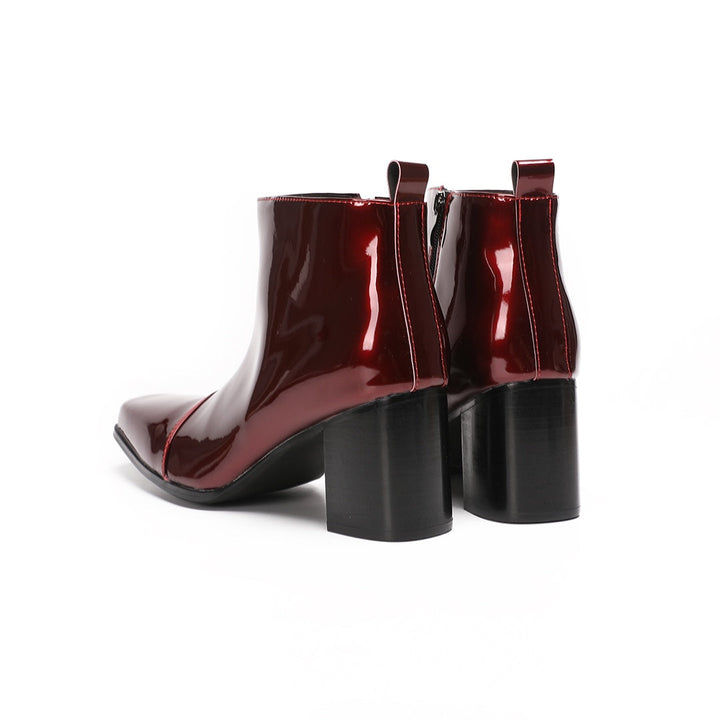 A pair of shiny burgundy patent leather ankle boots with a square toe and block heel, featuring a side zipper closure.