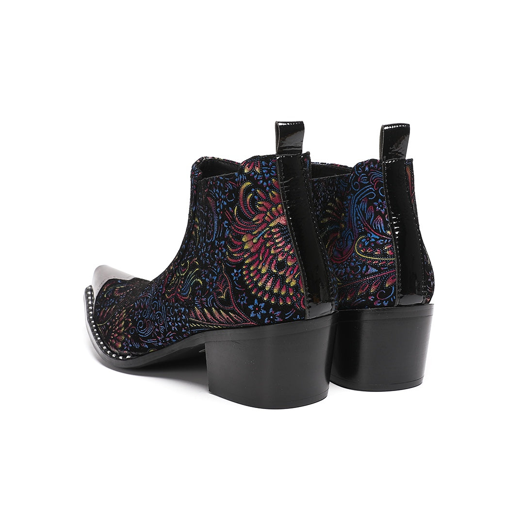 A pair of men's black ankle boots with a vibrant multicolor brocade pattern and a polished silver metal toe cap.