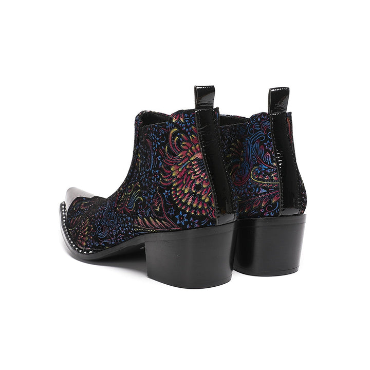 A pair of men's black ankle boots with a vibrant multicolor brocade pattern and a polished silver metal toe cap.