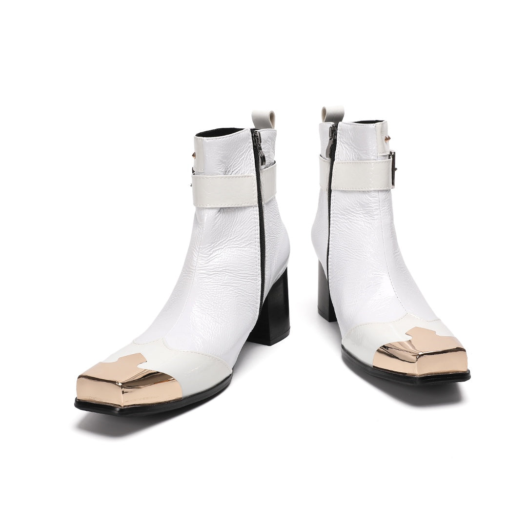 Pair of Dolashoes white patent leather ankle boots with gold metal square toe, studded buckle strap, and black block heel.