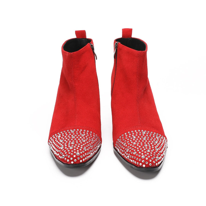 A pair of vibrant red suede ankle boots with silver rhinestones on the pointed toe and a black block heel.
