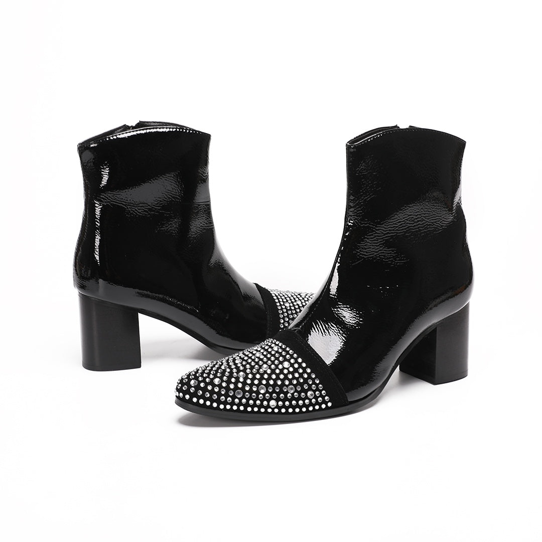 A pair of black patent leather ankle boots with rhinestone-embellished pointed toes and block heels.