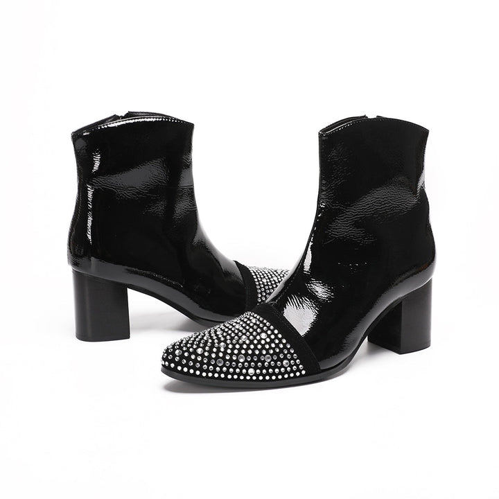 A pair of black patent leather ankle boots with rhinestone-embellished pointed toes and block heels.