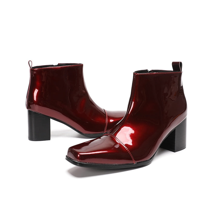 A pair of shiny burgundy patent leather ankle boots with a square toe and block heel, featuring a side zipper closure.