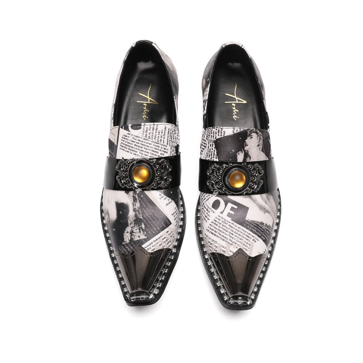 Pair of men's black and white newspaper print slip-on dress shoes with pointed silver metal toe caps and decorative buckles.