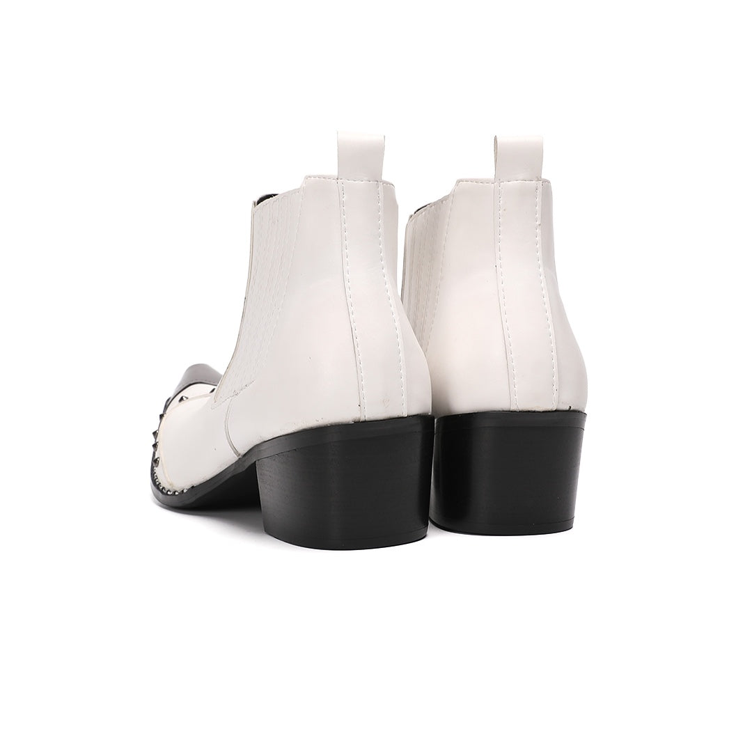 Pair of white studded Chelsea boots with silver metal toe caps and black heels on a white background.