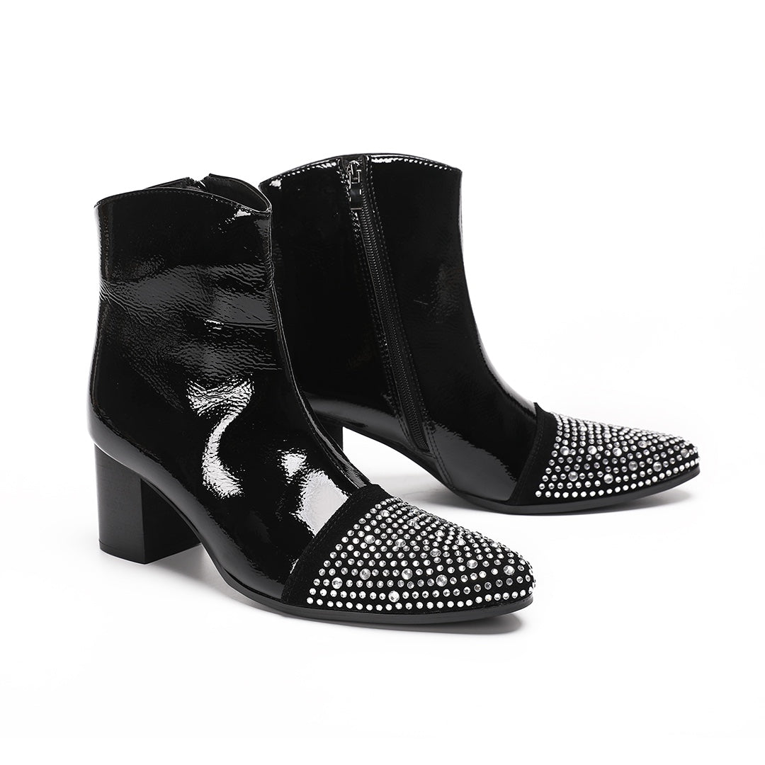 A pair of black patent leather ankle boots with rhinestone-embellished pointed toes and block heels.