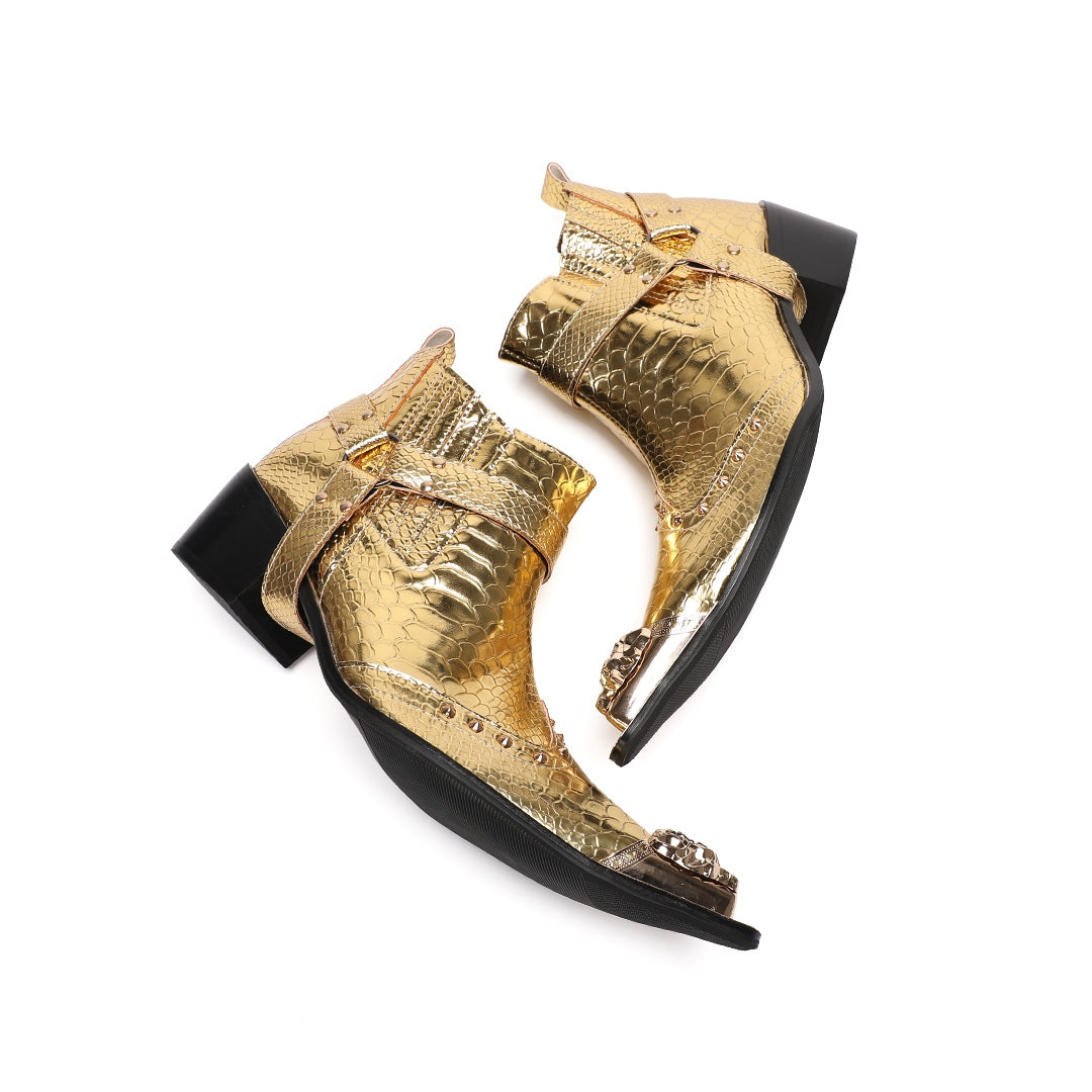 A pair of shiny gold snake skin textured ankle boots with a pointed metal toe cap, studded details, and an ankle strap.