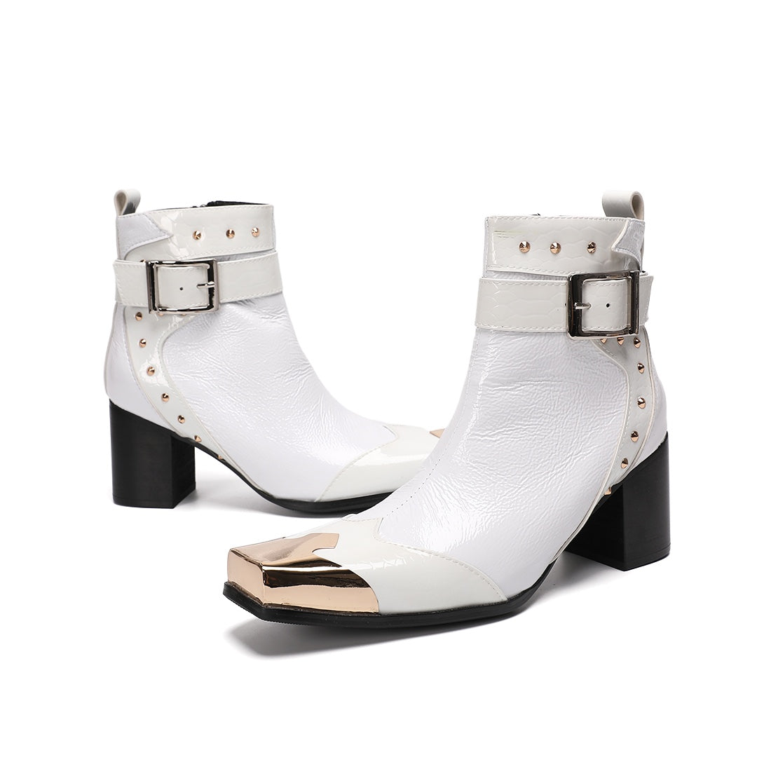 Pair of Dolashoes white patent leather ankle boots with gold metal square toe, studded buckle strap, and black block heel.