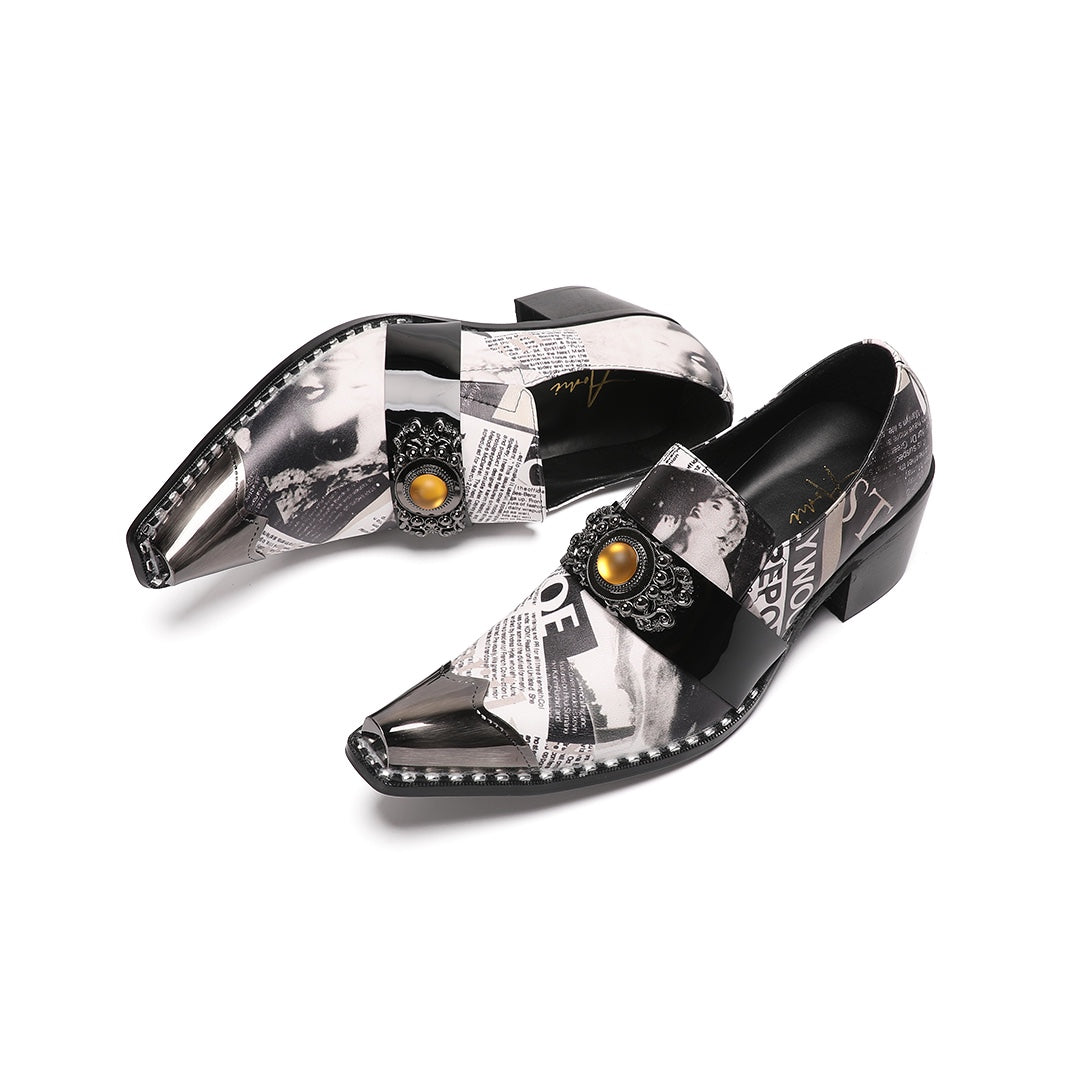 Pair of men's black and white newspaper print slip-on dress shoes with pointed silver metal toe caps and decorative buckles.