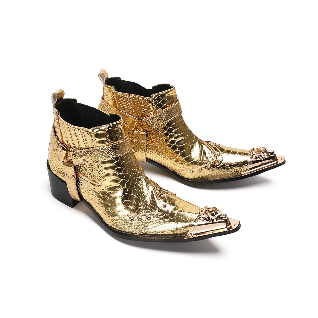 A pair of shiny gold snake skin textured ankle boots with a pointed metal toe cap, studded details, and an ankle strap.