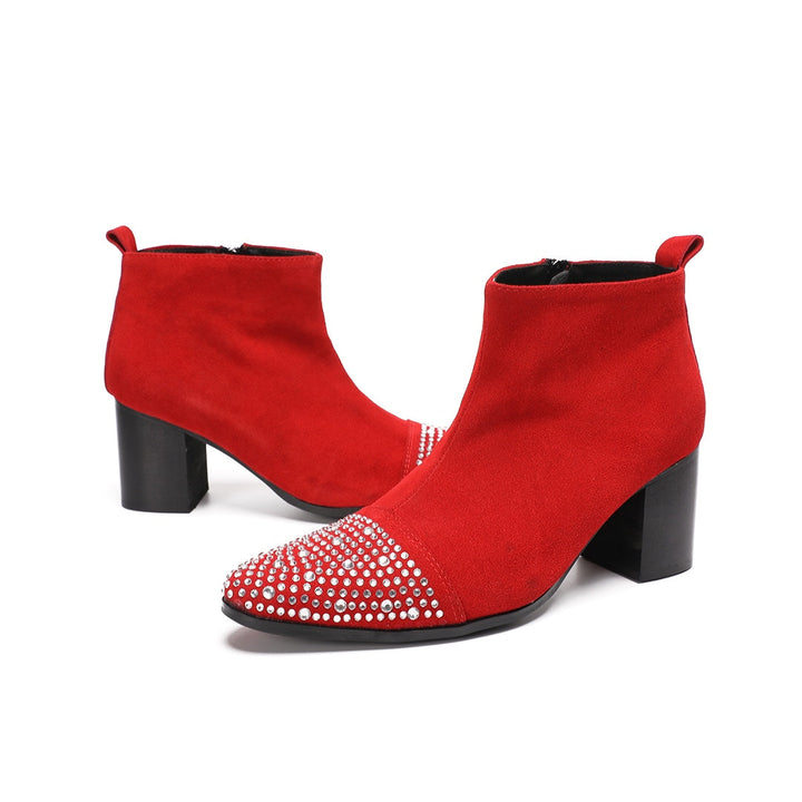 A pair of vibrant red suede ankle boots with silver rhinestones on the pointed toe and a black block heel.