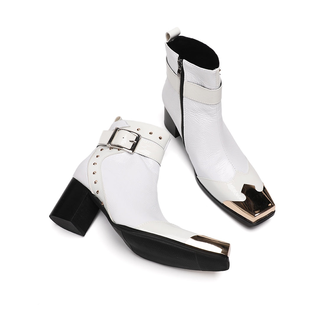 Pair of Dolashoes white patent leather ankle boots with gold metal square toe, studded buckle strap, and black block heel.