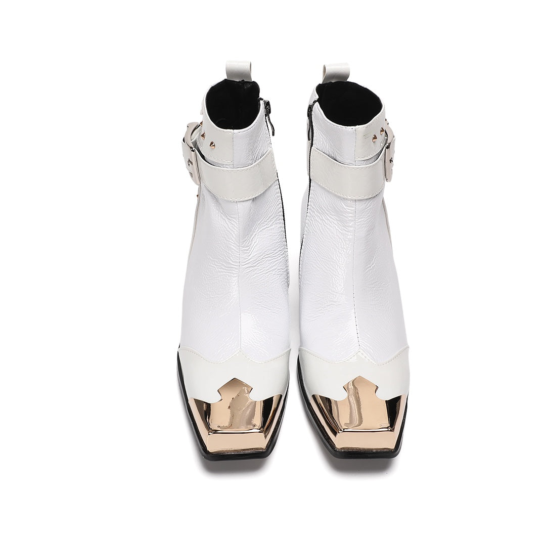 Pair of Dolashoes white patent leather ankle boots with gold metal square toe, studded buckle strap, and black block heel.