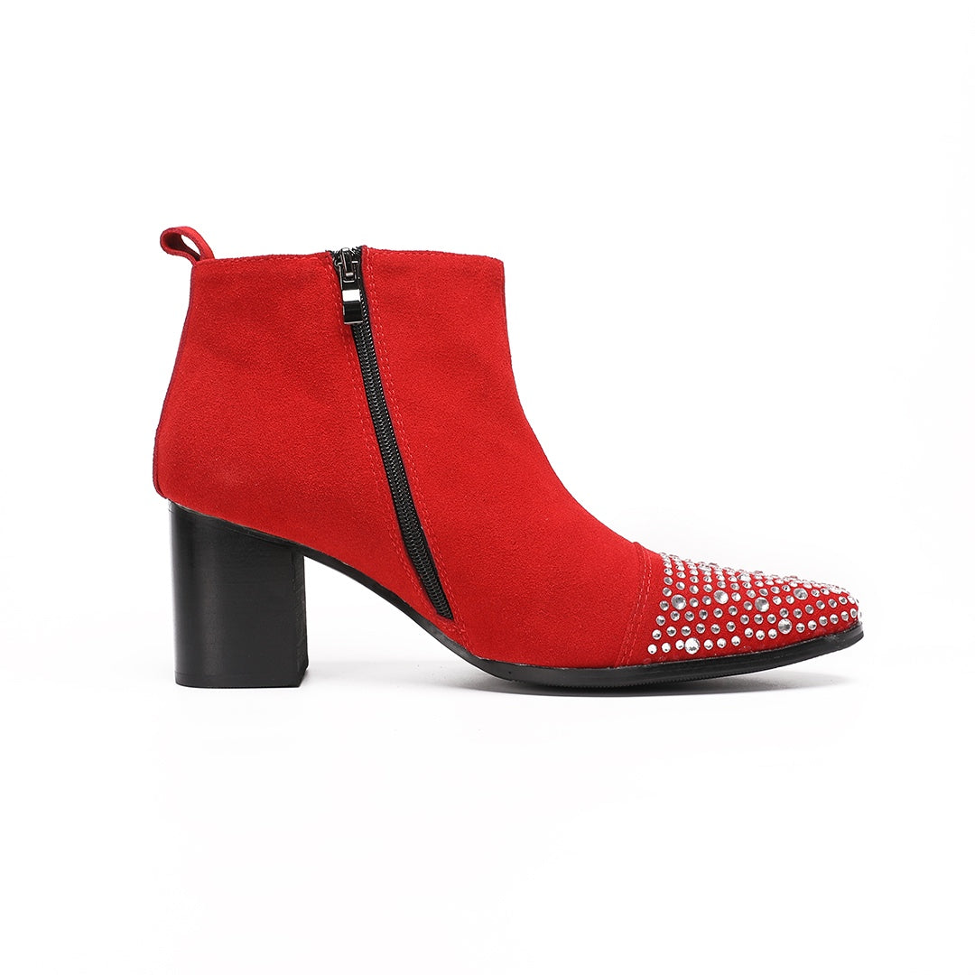 A pair of vibrant red suede ankle boots with silver rhinestones on the pointed toe and a black block heel.