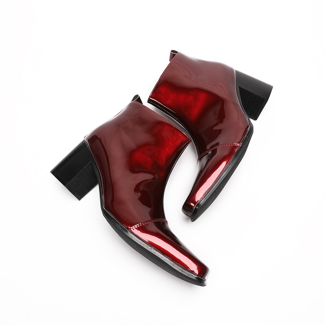 A pair of shiny burgundy patent leather ankle boots with a square toe and block heel, featuring a side zipper closure.