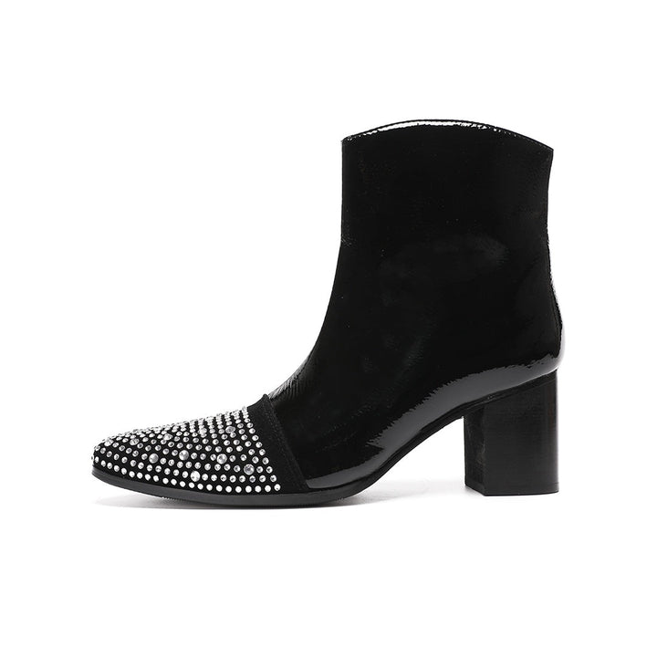 A pair of black patent leather ankle boots with rhinestone-embellished pointed toes and block heels.