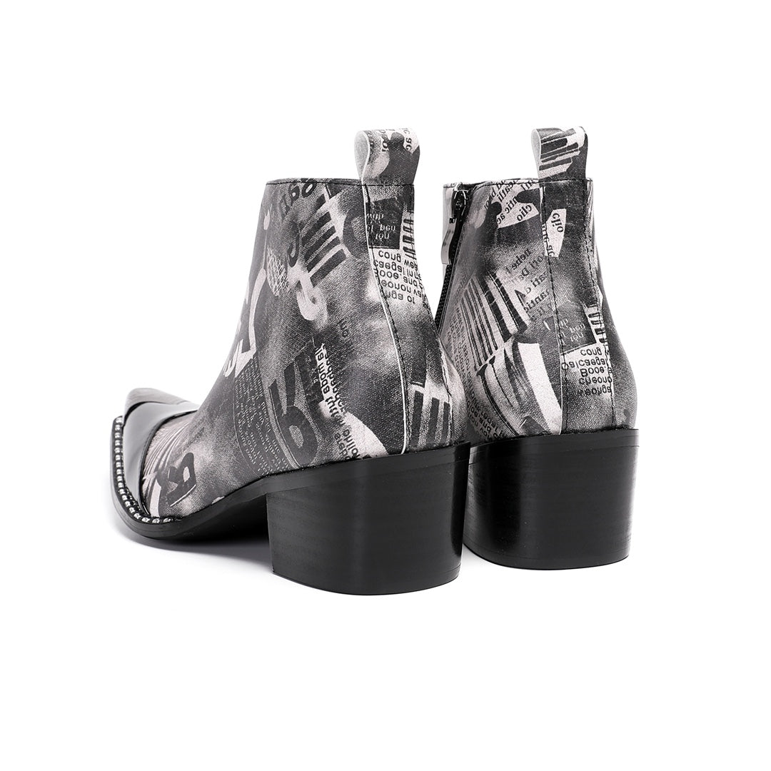 Pair of men's black and white newspaper print ankle boots with a shiny black pointed toe and silver metal tip, side zipper