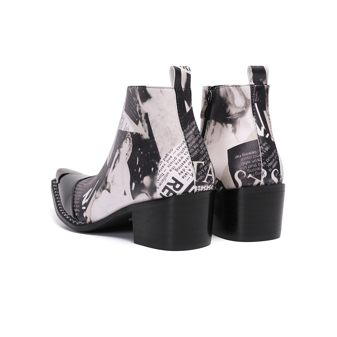 Pair of men's black and white newspaper print ankle boots with pointed patent leather toe and metal tip, side zipper, and