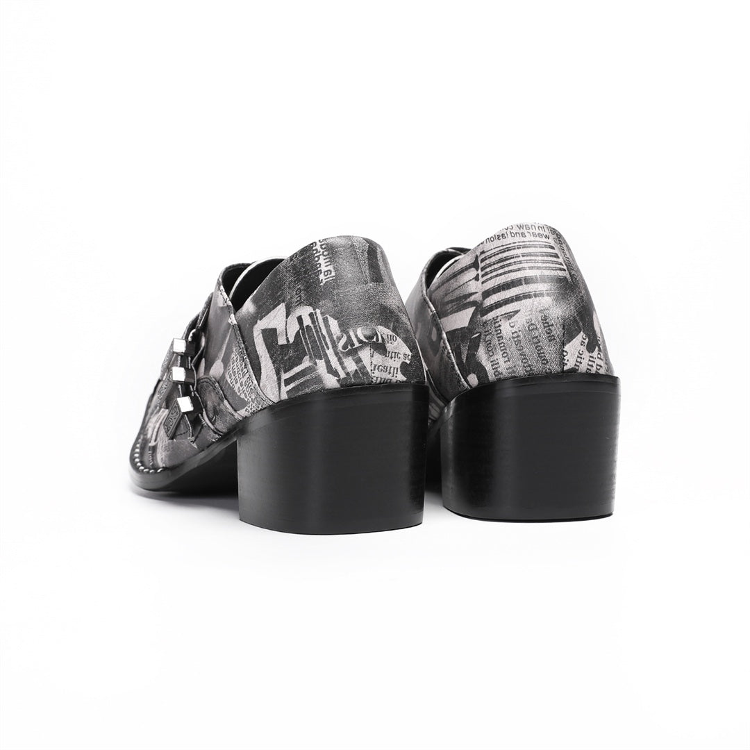 Pair of men's high heel derby shoes with a black and white newspaper print, pointed metal toe caps, and buckle details, shown
