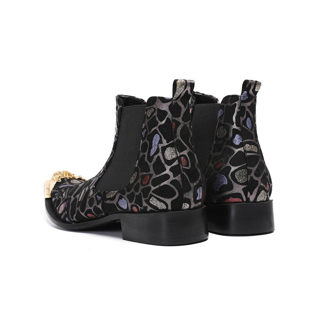 Pair of men's black Chelsea boots with a metallic leopard print pattern and ornate gold metal toe caps, shown on a white
