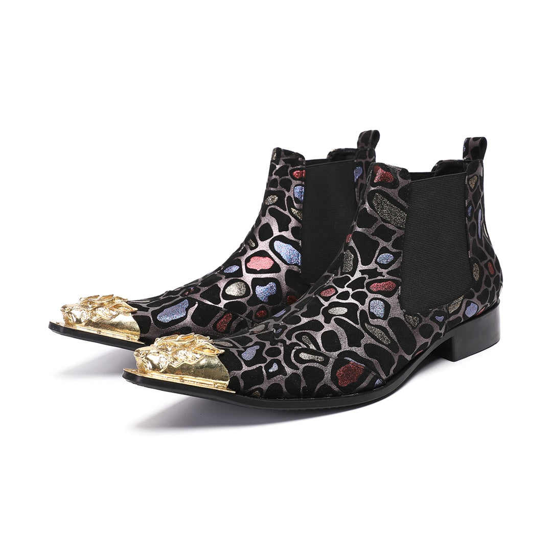 Pair of men's black Chelsea boots with a metallic leopard print pattern and ornate gold metal toe caps, shown on a white