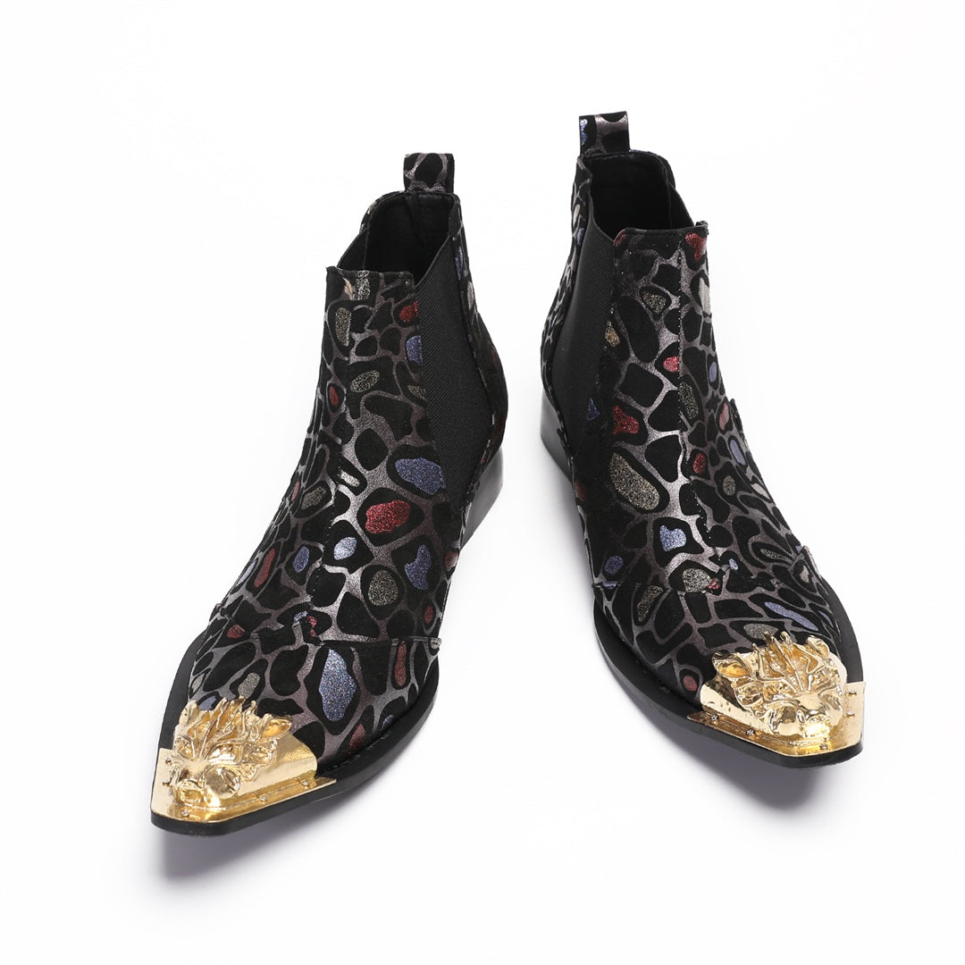Pair of men's black Chelsea boots with a metallic leopard print pattern and ornate gold metal toe caps, shown on a white