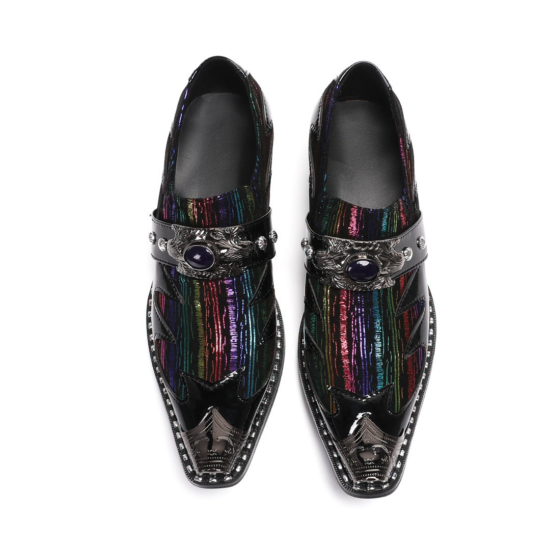 A single black patent leather men's dress shoe with a pointed metal toe, rainbow-striped vamp, and a decorative silver buckle