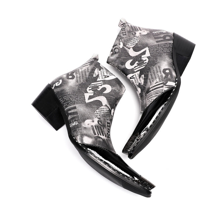 Pair of men's black and white newspaper print ankle boots with a shiny black pointed toe and silver metal tip, side zipper