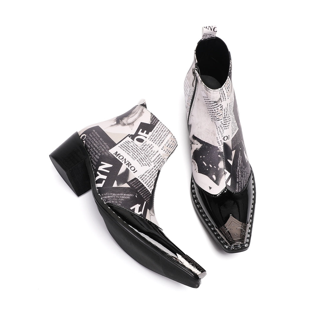 Pair of men's black and white newspaper print ankle boots with pointed patent leather toe and metal tip, side zipper, and