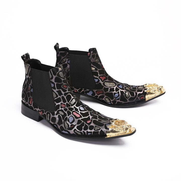 Pair of men's black Chelsea boots with a metallic leopard print pattern and ornate gold metal toe caps, shown on a white
